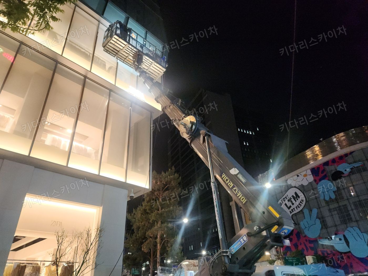 조명이 켜진 상가 외벽 앞 야간 장비 배치