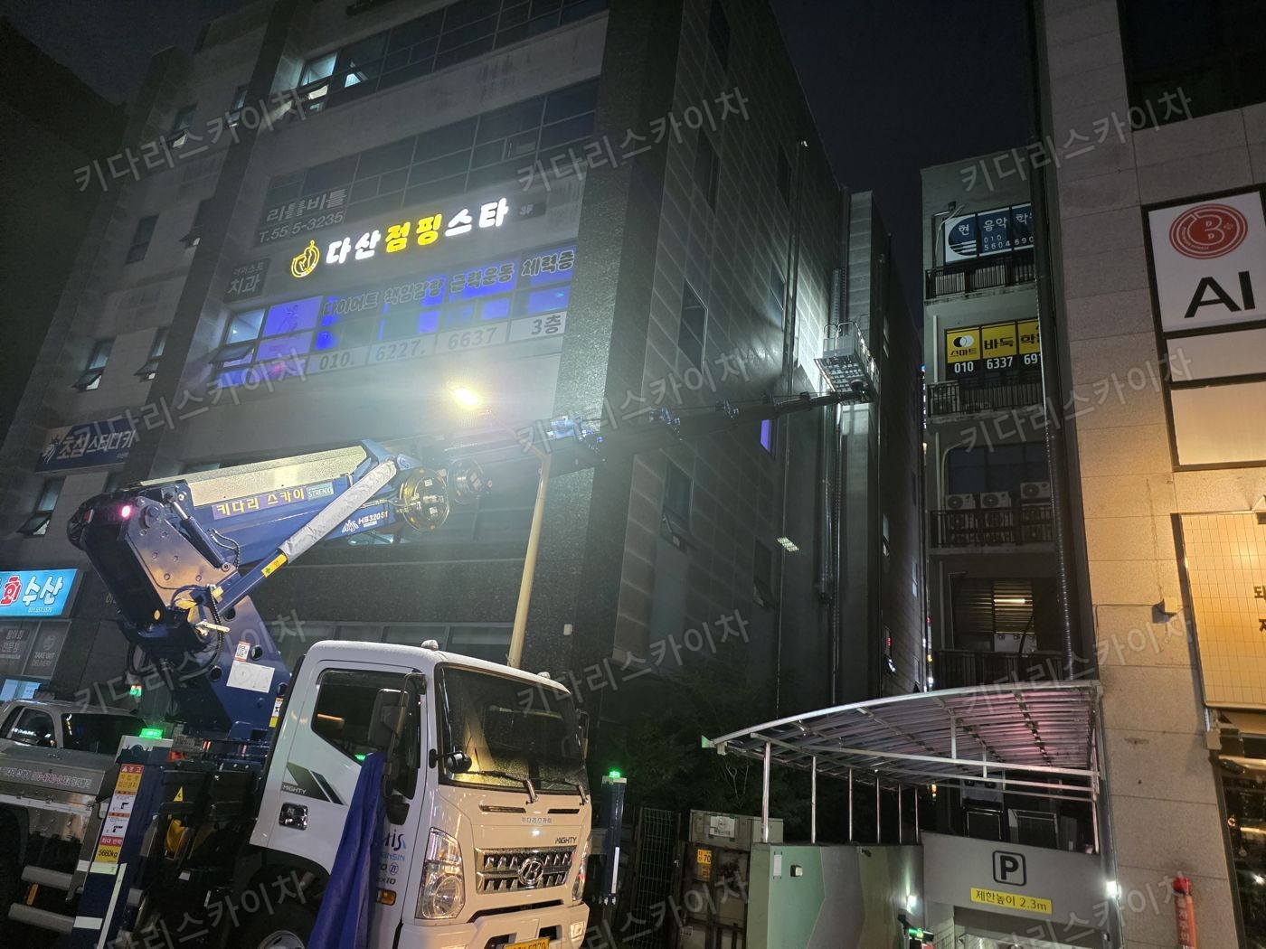 조명이 켜진 상가 외벽 앞 야간 장비 배치